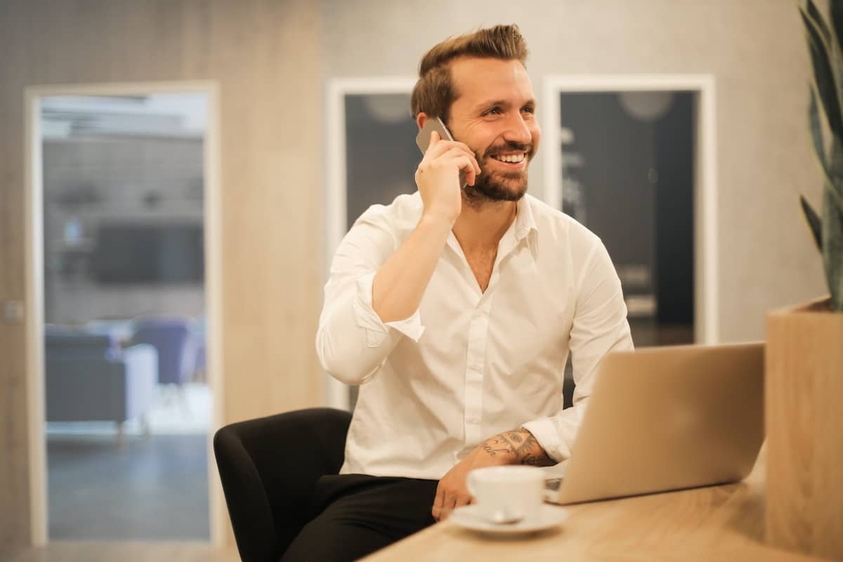 man smiling on the phone with his laptop open