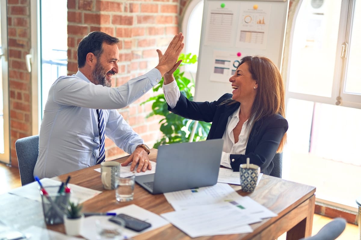 two people high-fiving after finding the best business brokerage accounts