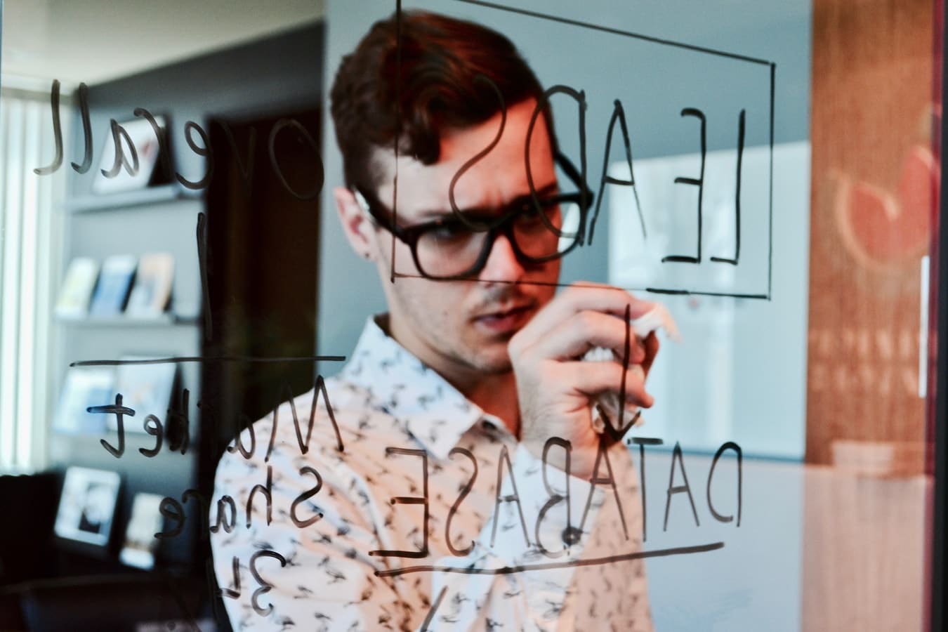 man writing on a clear board