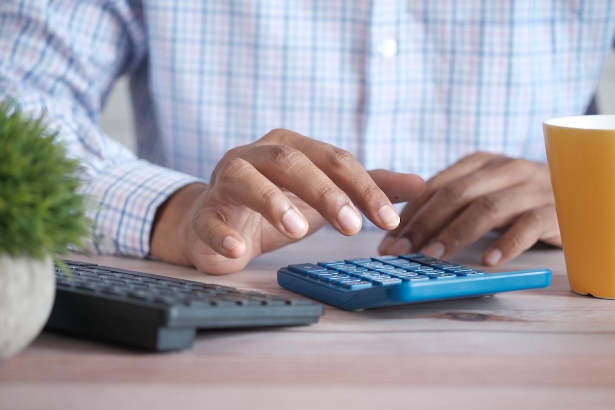 A black man's hands typing on a calculator, highlighting financial calculations and accounting.