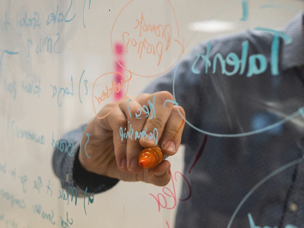 man drawing on a dry erase board